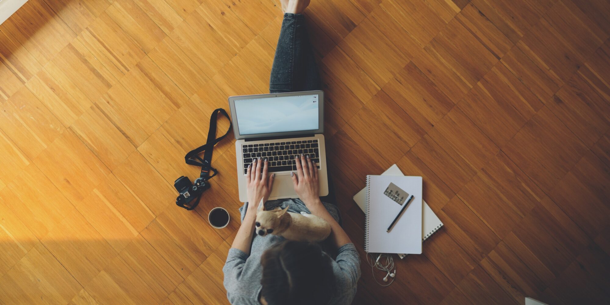 top view of a female student relaxes sitting on a wooden floor at home and chooses suitable online courses. young businesswoman typing text message on laptop keyboard. Vintage camera, credit card
