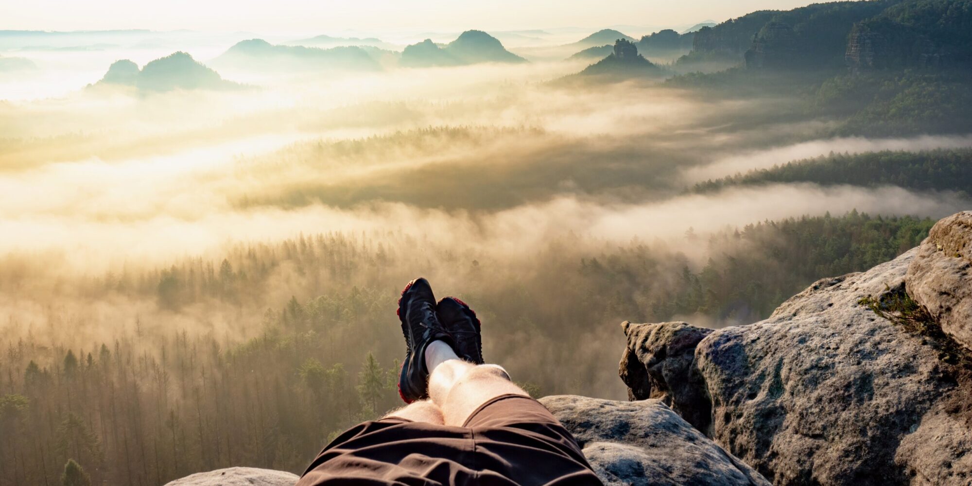 First person view to resting hiking legs,resting during hike. High rocks, clear sky and sun,